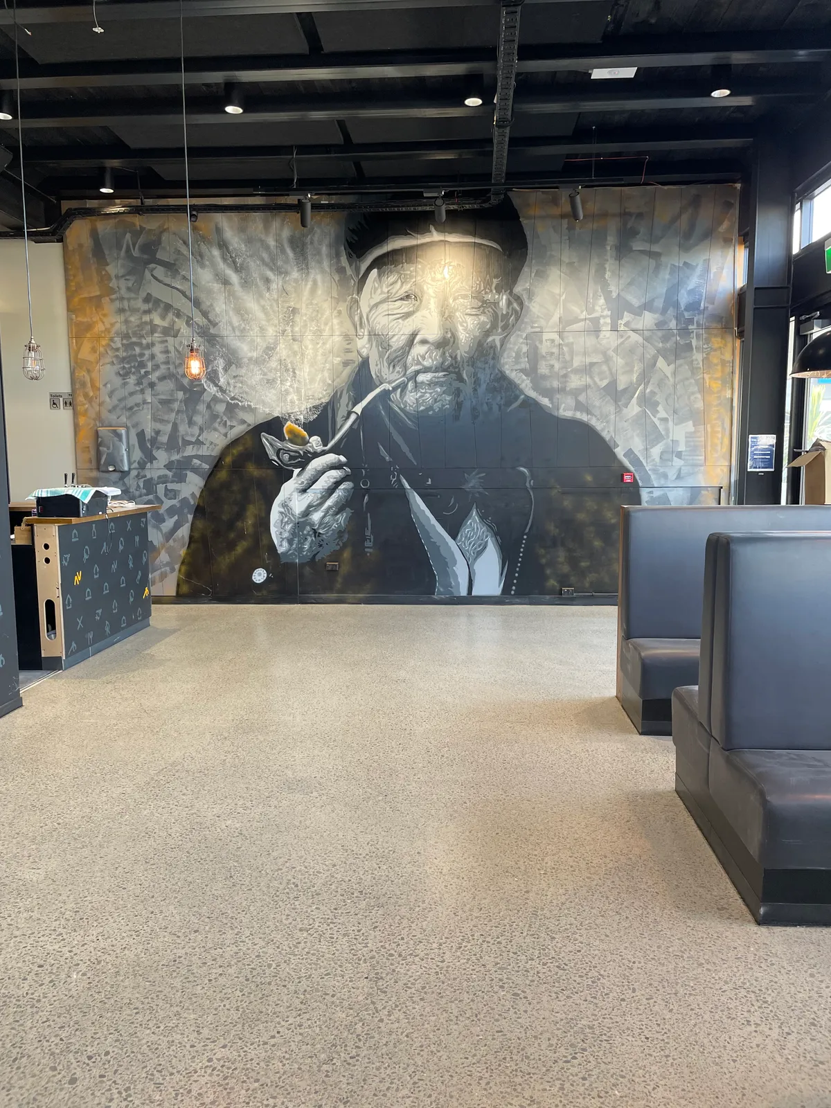 Polished concrete floor at Vagabond restaurant featuring dramatic chef portrait wall art