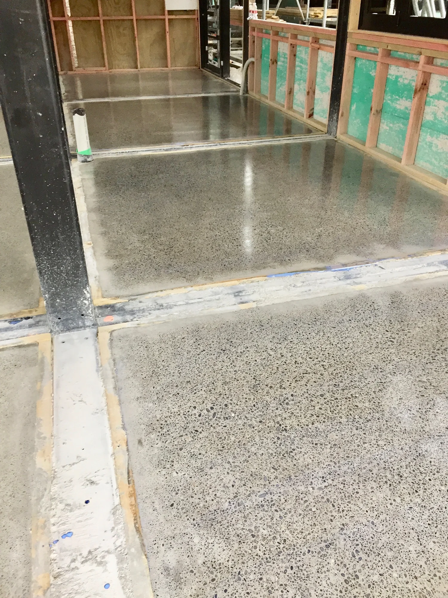 Wax-sealed exposed-aggregate concrete floor inside a timber-framed building